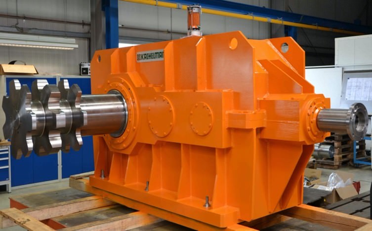 In der Fertigungshalle von der Firma KACHELMANN GETRIEBE GmbH wird ein Kegelstirnradgetriebe mit Hohlwelle zur Aufnahme der Kettenschaftwelle gefertigt. Das Sondergetriebe ist Orange und steht auf einigen Paletten. KACHELMANN GETRIEBE GmbH